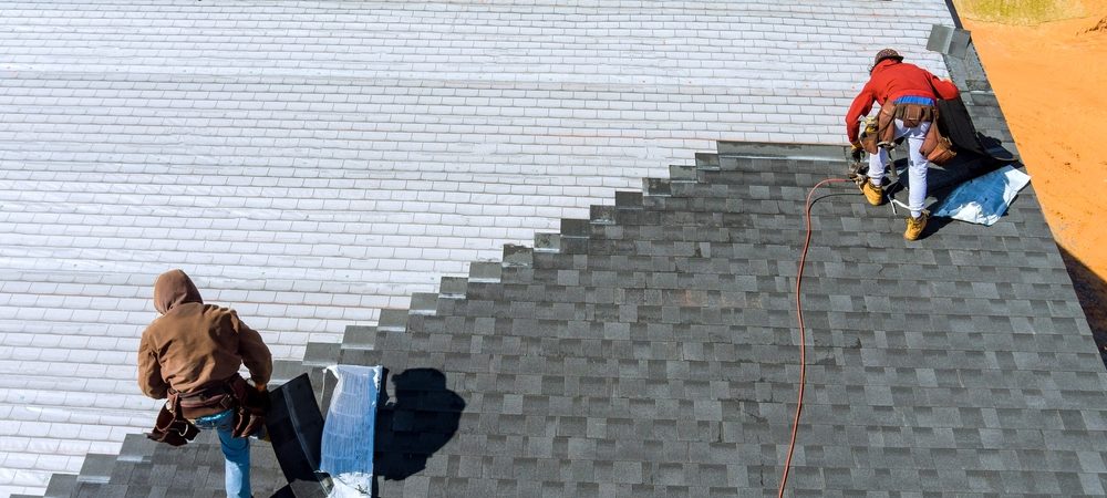 two roofers repairing a house