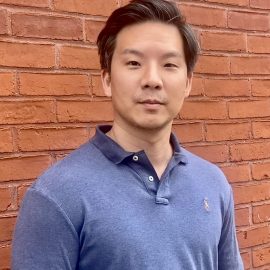 author David Kim standing against a brick wall
