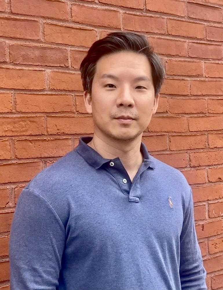author David Kim standing against a brick wall